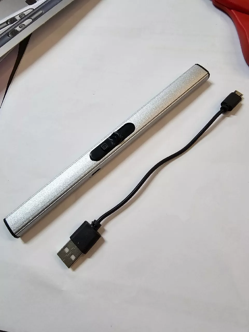 ด้ามจุดไฟไฟฟ้าสีเงินวางคู่กับสายชาร์จ Micro USB รูปจริงจากลูกค้า CK0025